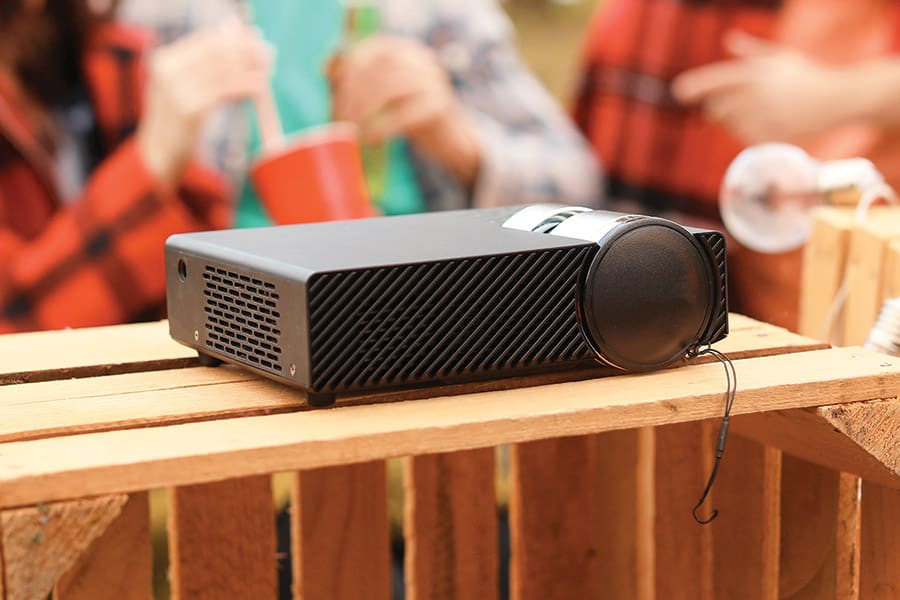 Outdoor projector during the day with people behind it.