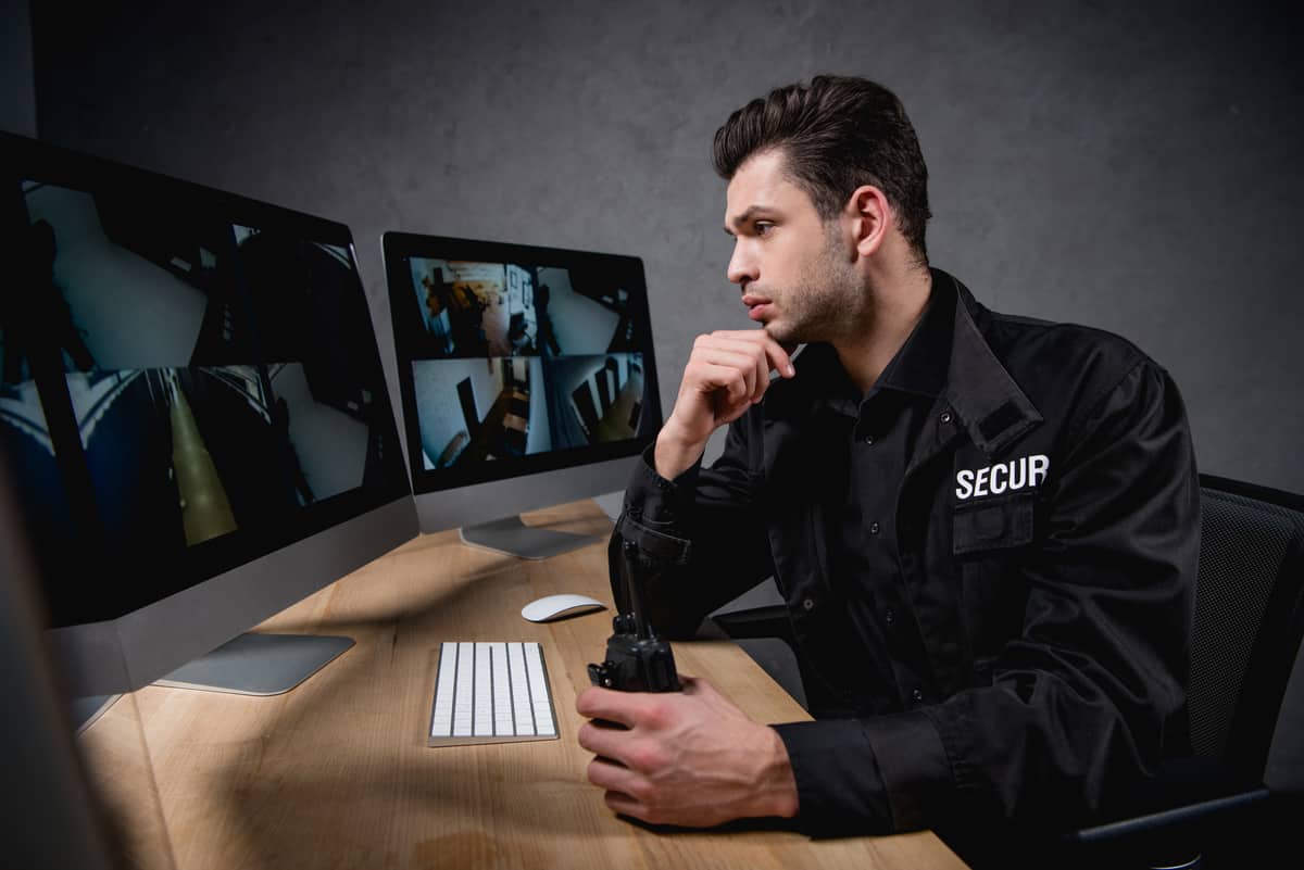 A security guard looking at camera feeds on computer monitors