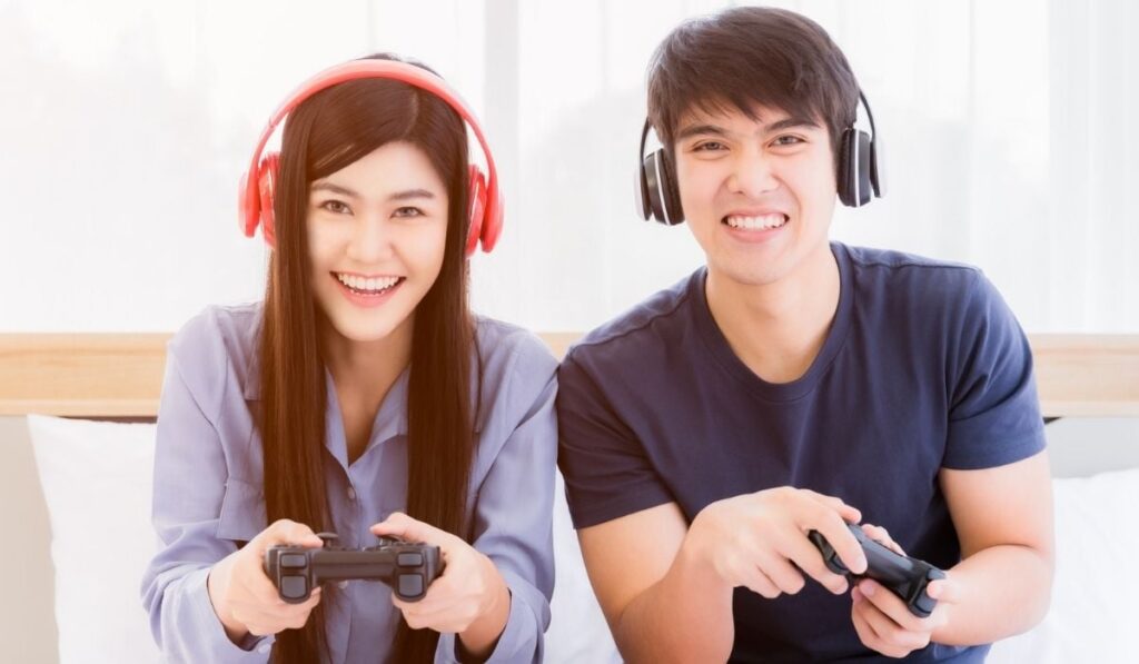 Happy young couple wear headphone and holding joystick playing video game 