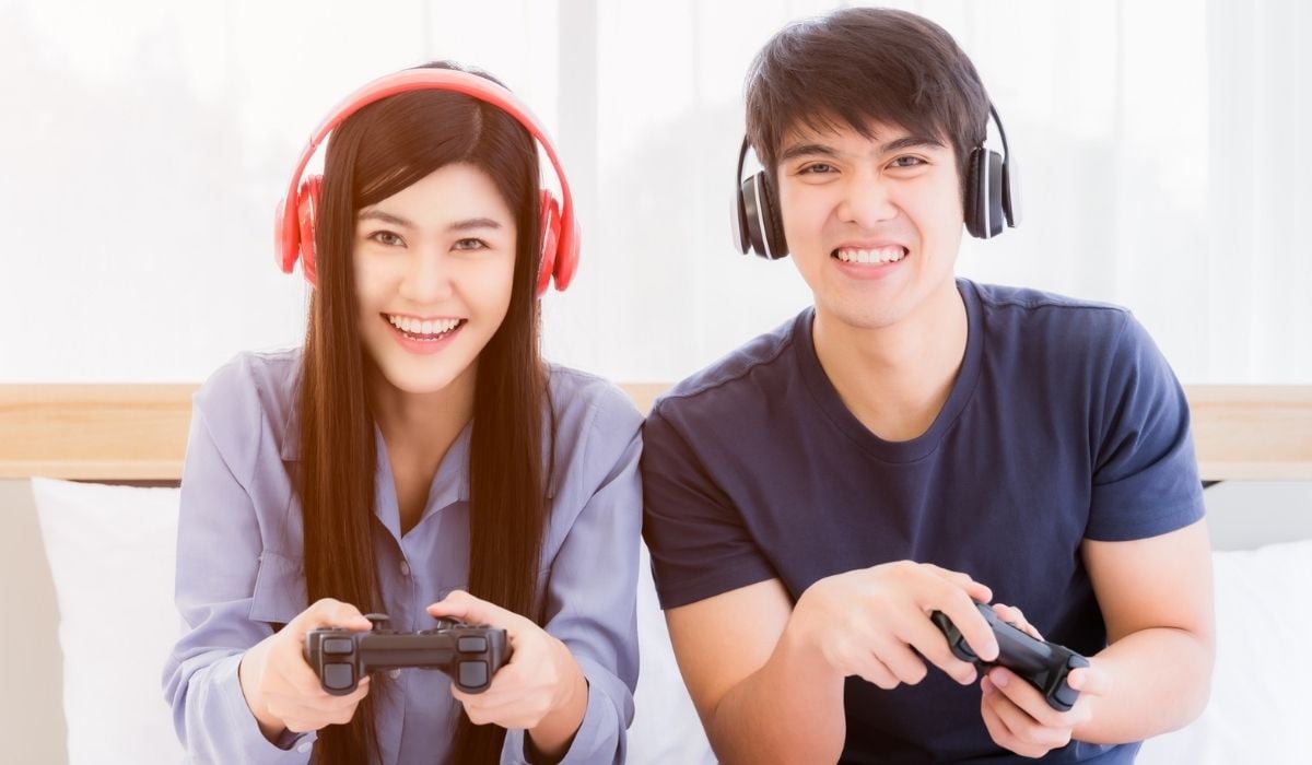 Happy young couple wear headphone and holding joystick playing video game