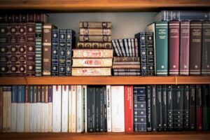 Lots of books across two bookshelves, some books stacked neatly, others piled on top of each-other randomly.