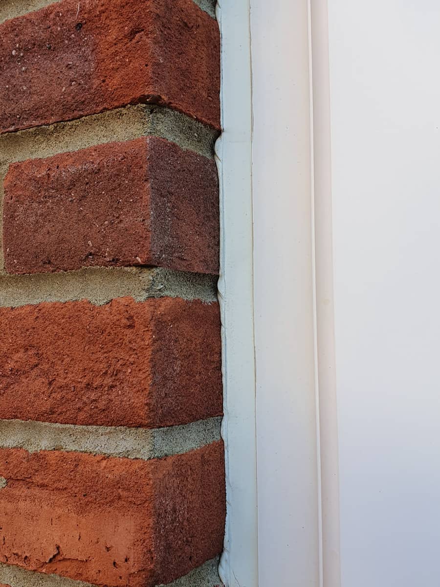 A very close up view of a thin UPVC door frame panel, with a brick wall to the left which would block lots of a wide-angle lens video capture.