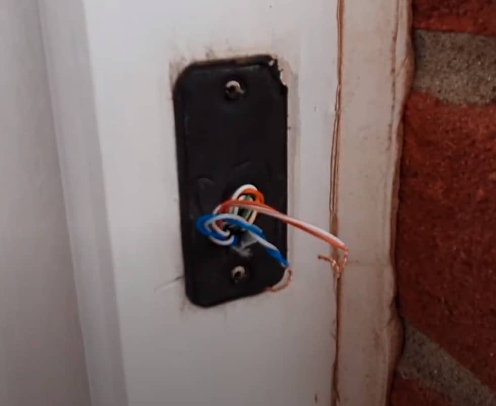 A removed doorbell, showing the two supply wires (blue and orange twisted pairs).