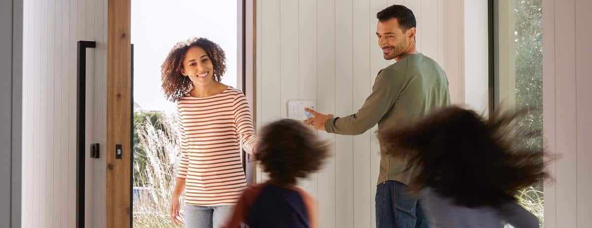 A Ring Alarm keypad by the front door, with the dad activating it and the mum coming to get the two children.