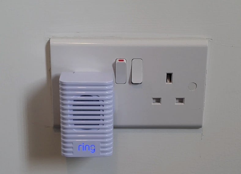 My Ring Chime plugged into a UK plug socket, with "ring" illuminated in blue light.