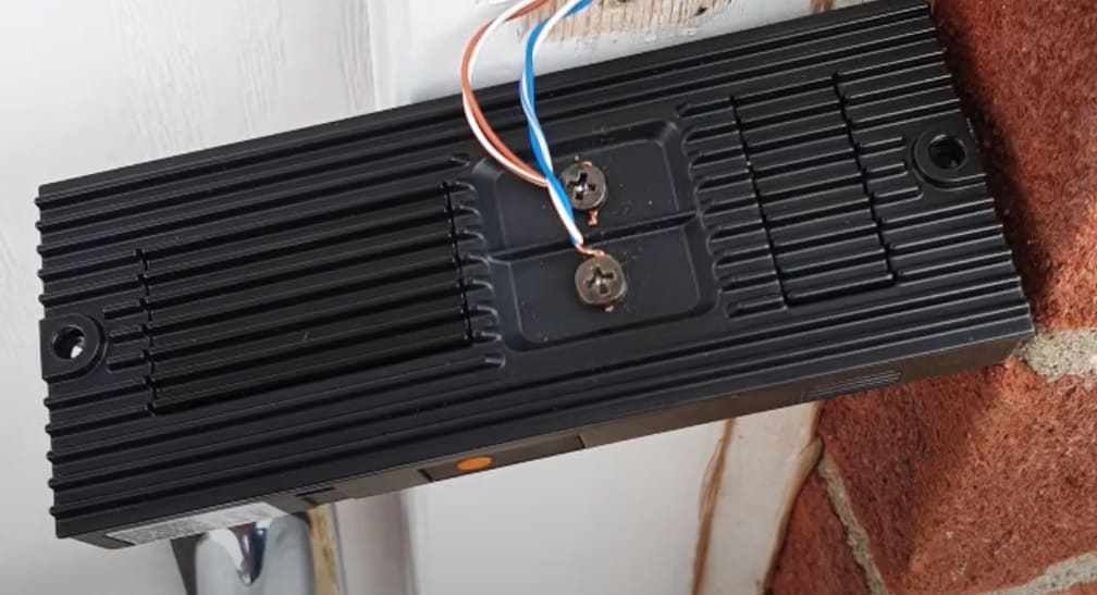 A Ring Doorbell Pro wired off (but off the door) showing the ribbed vertical heatsinks running down the back.