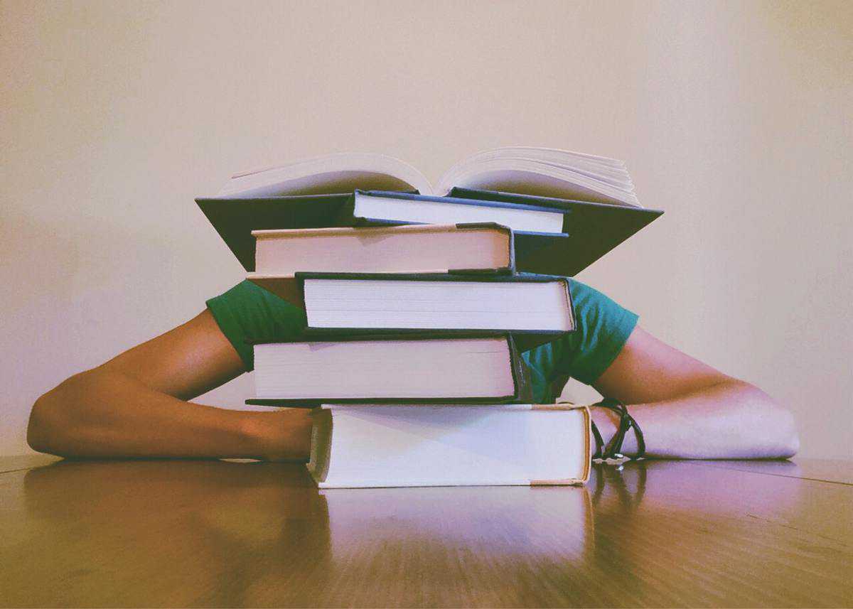 Person hiding behind stacks of books