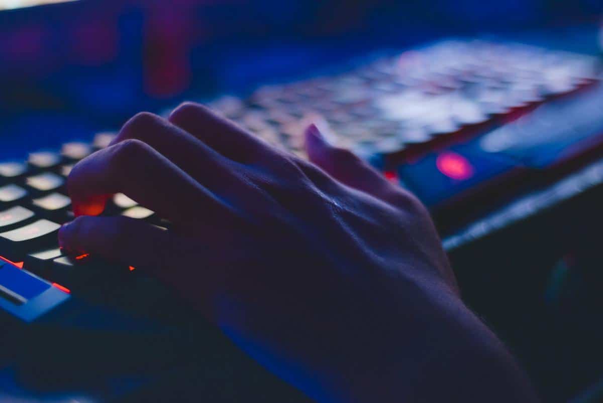 Someone's hand on a LED-lit keyboard.