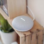 A Google Home Mini device placed on a wooden shelving unit