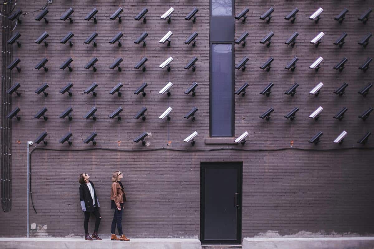 Two people standing under lots of bullet CCTV cameras