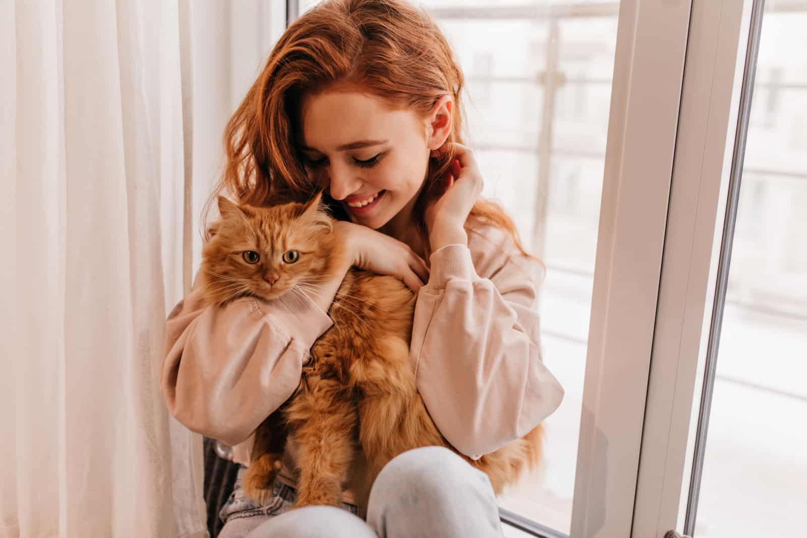 redheaded woman holding an orange cat