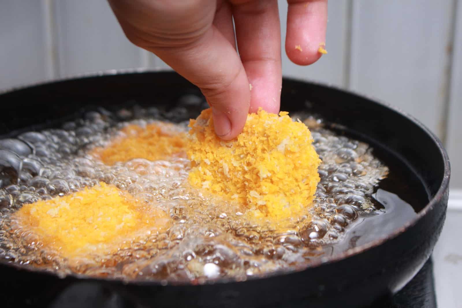 Close up image of chef hand putting chicken nuggets tempura in to hot oil pan