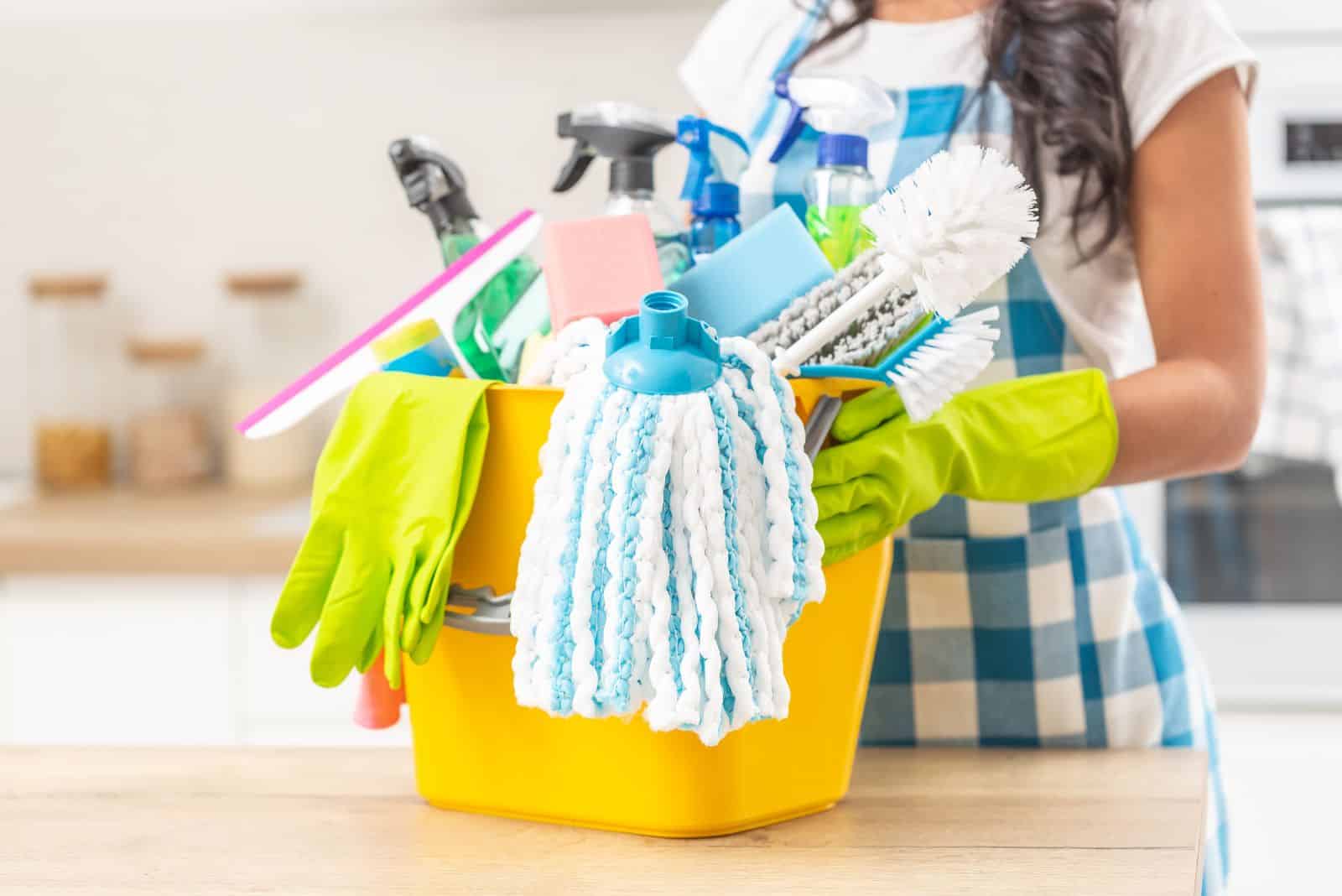 the woman is holding a bucket for cleaning the house