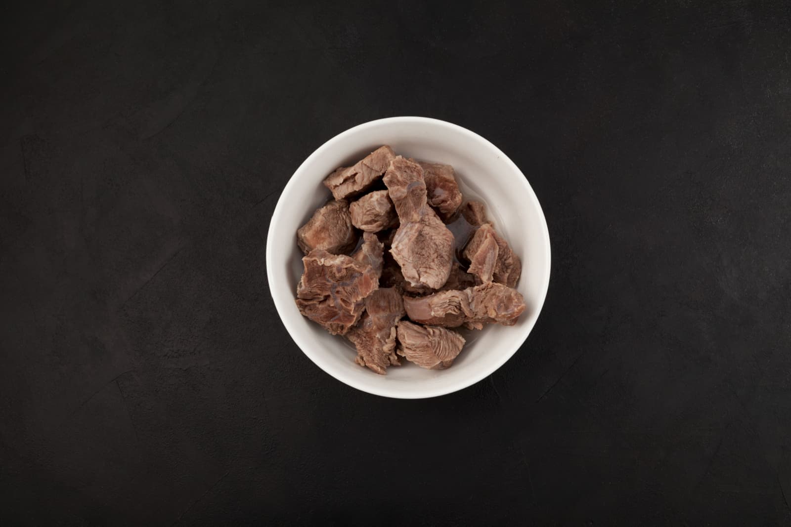 Pieces of beef or lamb in white bowl