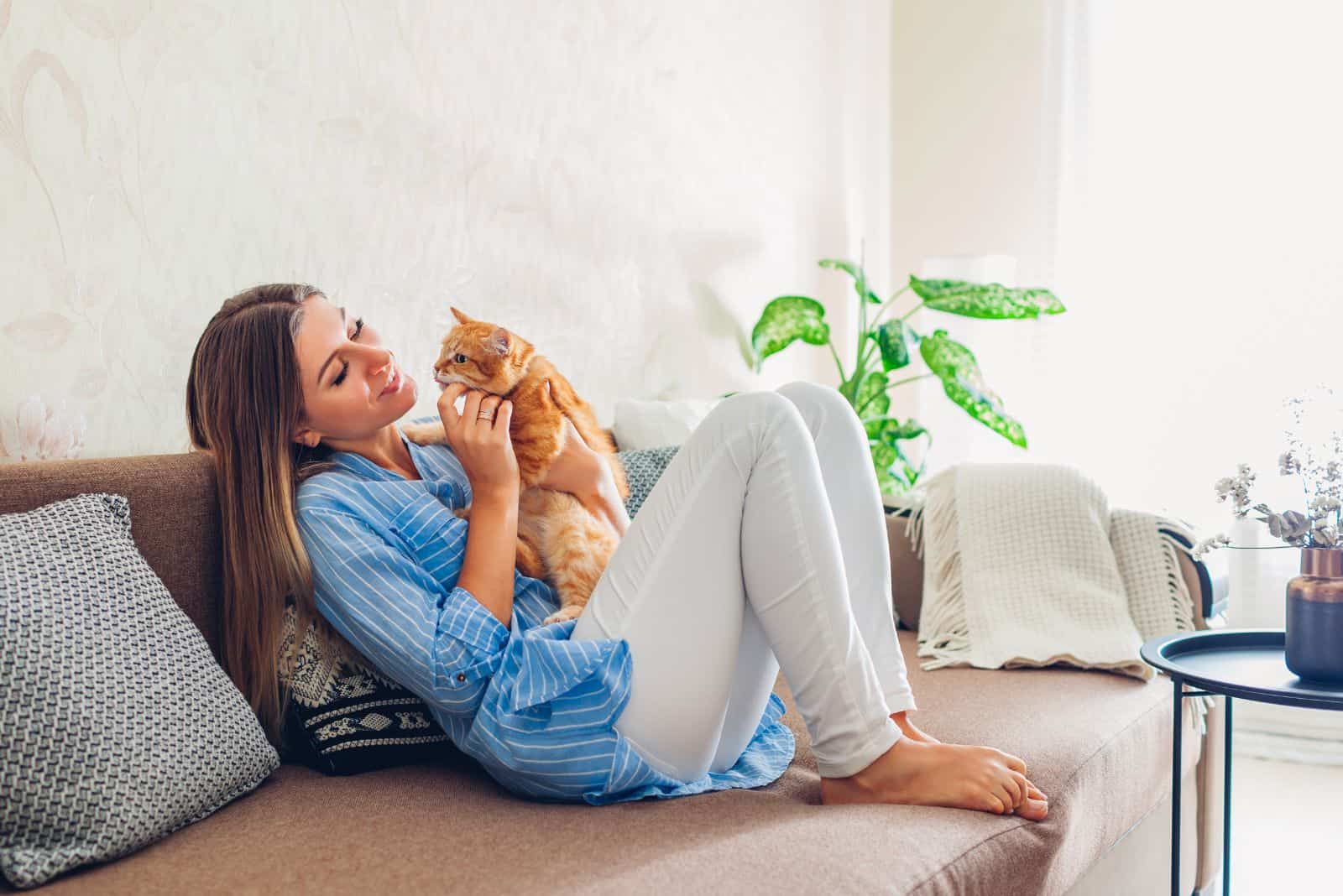 a smiling young girl is playing with a cat