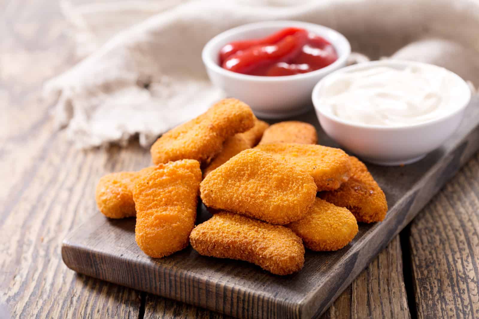 chicken nuggets with sauces on wooden board