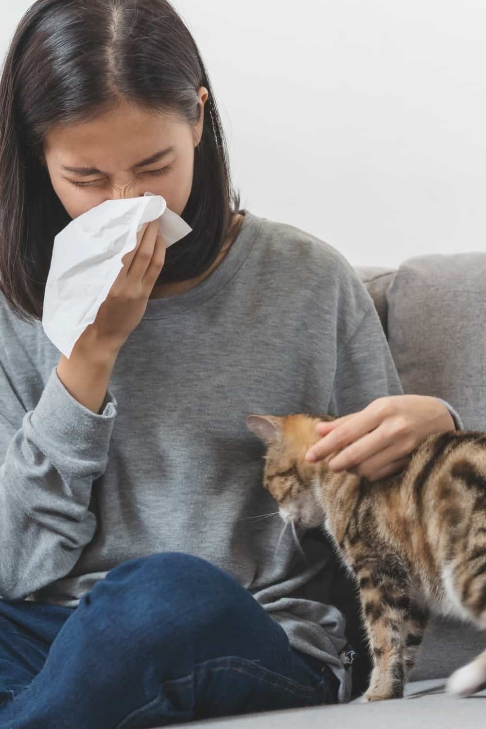 woman sneezing next to a cat