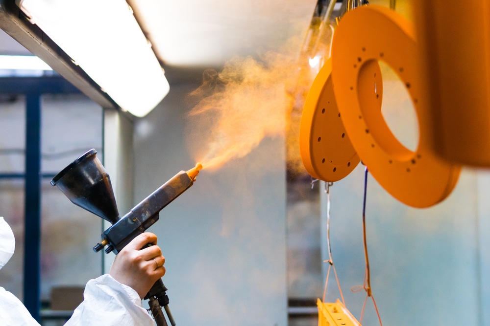 A Woman In A Protective Gear Powder Coating Metal Parts