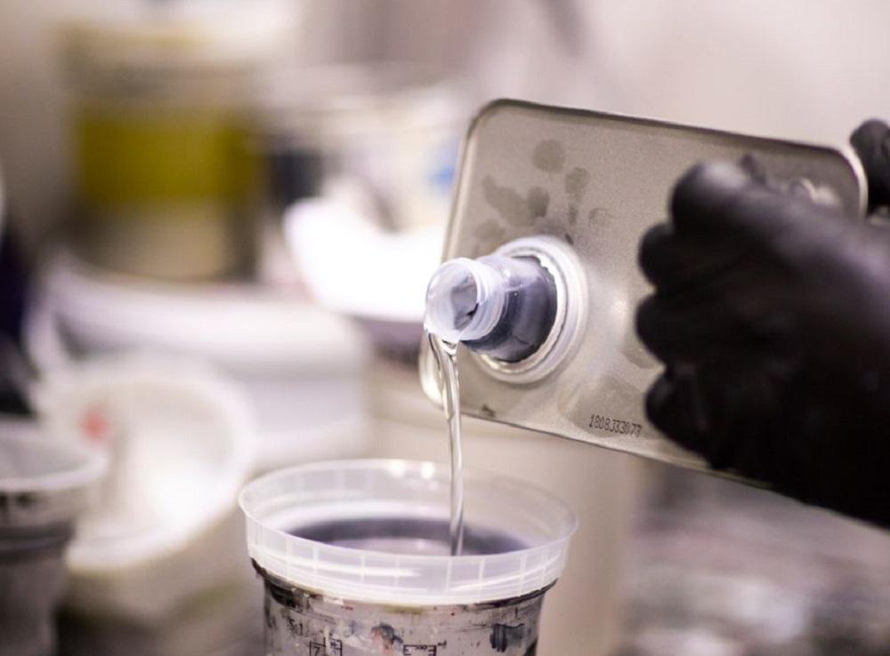 Pouring a paint thinner in a mixing container in a workshop