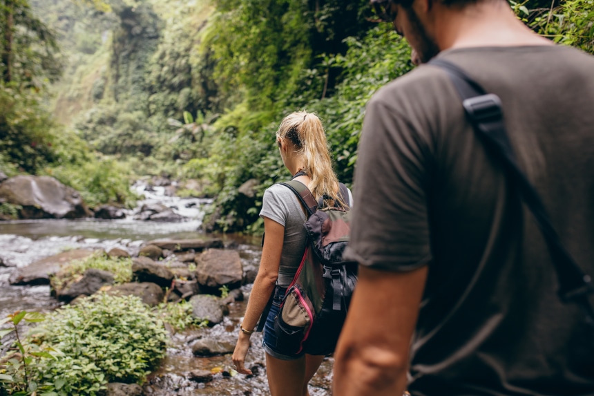 A couple hiking by a stream in a rainforest