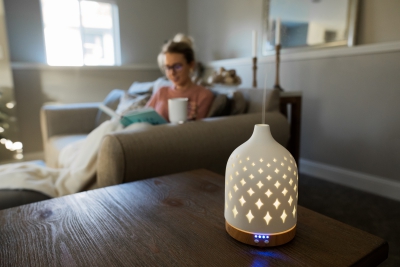 Essential oil diffuser with a woman relaxing on a couch