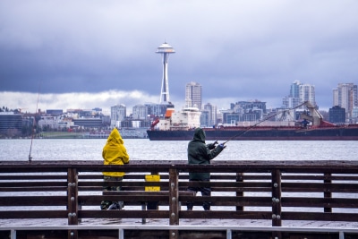 Two people fishing off a dock on a rainy day in Seattle