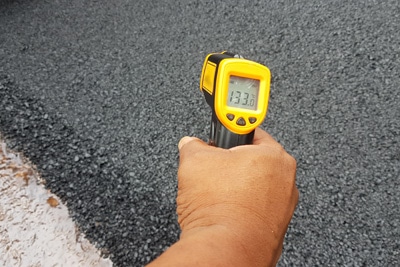 IR thermometer measuring temperature of asphalt