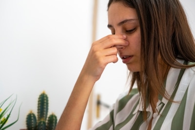 Woman pinching her nose to stop a nosebleed