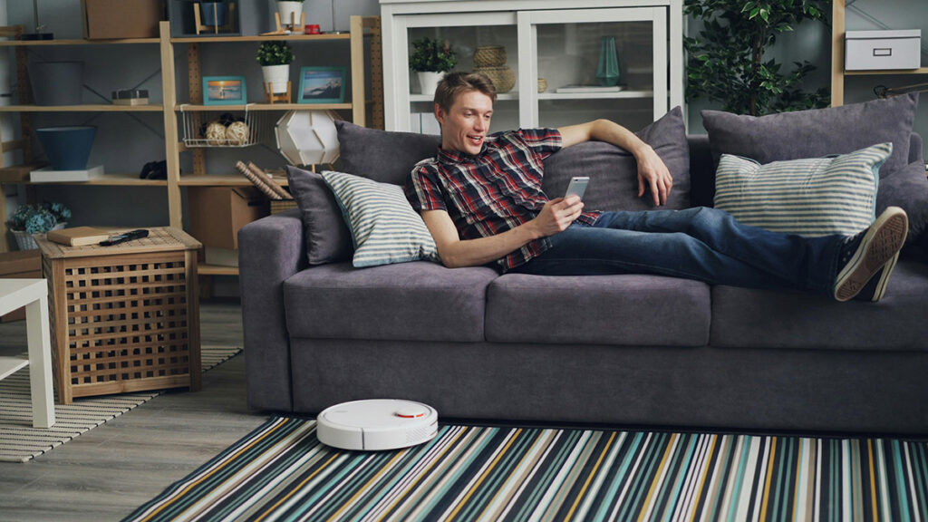 photo of a man controlling his robot vacuum